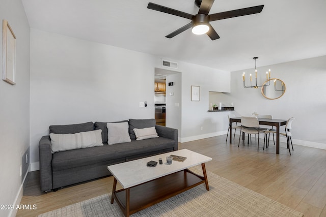 living room featuring ceiling fan with notable chandelier and light hardwood / wood-style floors