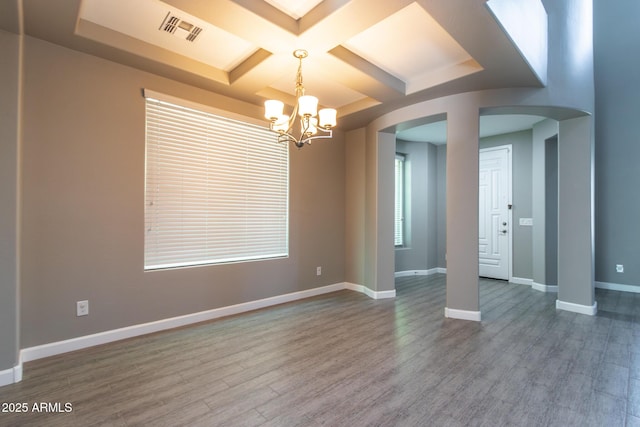 empty room featuring coffered ceiling, wood-type flooring, beamed ceiling, and an inviting chandelier