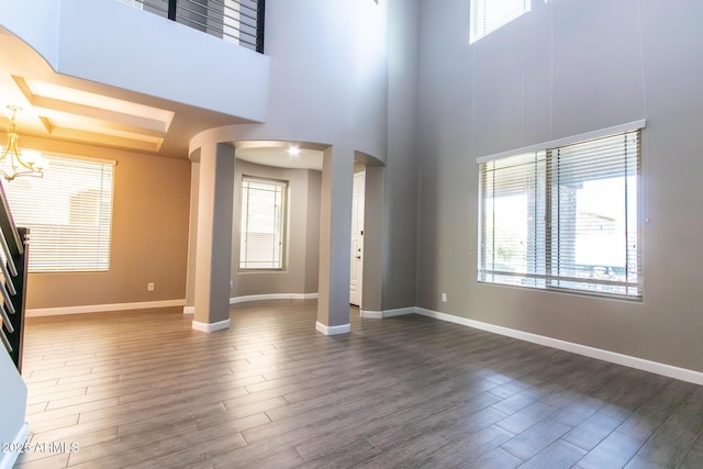 unfurnished living room featuring a towering ceiling and a chandelier