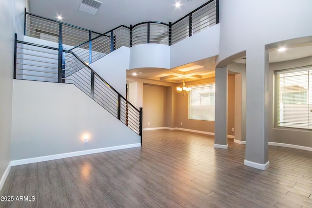 unfurnished living room with hardwood / wood-style flooring, a towering ceiling, and a wealth of natural light