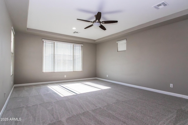 carpeted empty room with a tray ceiling and ceiling fan