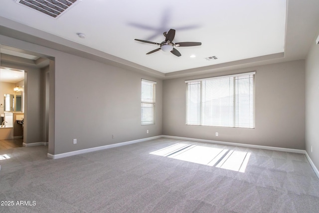 carpeted spare room featuring a raised ceiling and ceiling fan