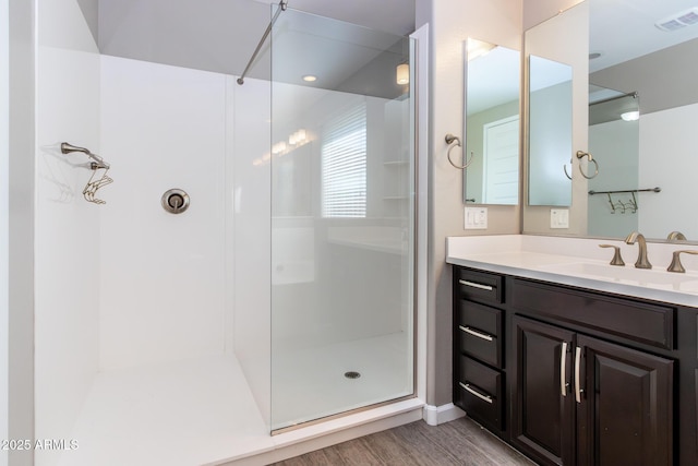 bathroom with hardwood / wood-style flooring, vanity, and walk in shower