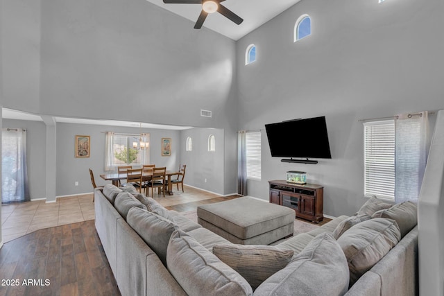 living room with visible vents, plenty of natural light, baseboards, and ceiling fan with notable chandelier