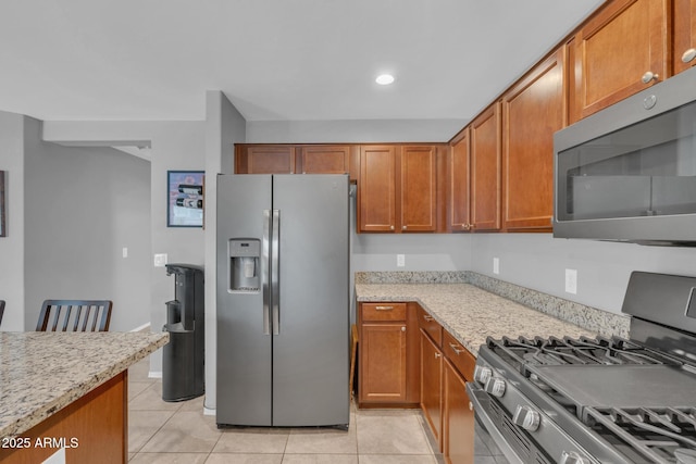 kitchen featuring light tile patterned floors, stainless steel appliances, and brown cabinets