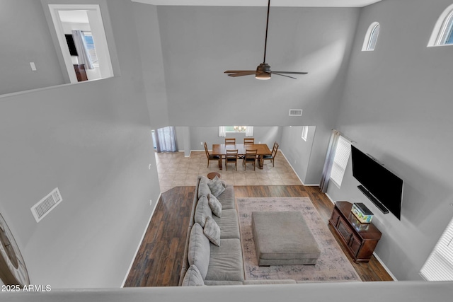 living room with visible vents, wood finished floors, baseboards, and ceiling fan