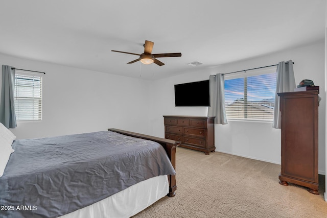 bedroom featuring visible vents, baseboards, light colored carpet, and a ceiling fan