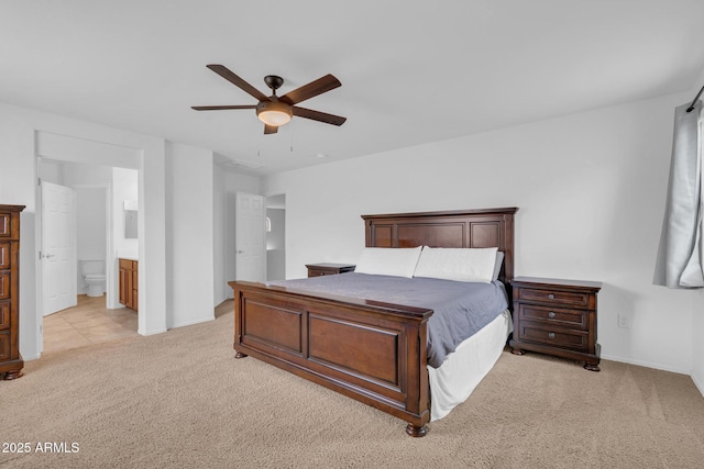 bedroom with a ceiling fan, ensuite bath, light colored carpet, and baseboards