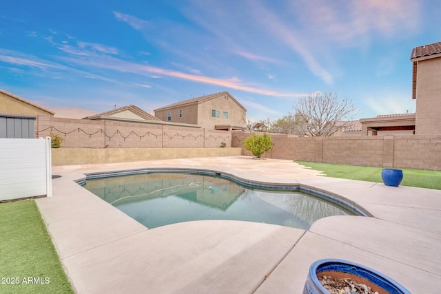 pool at dusk with a patio, a fenced backyard, and a fenced in pool