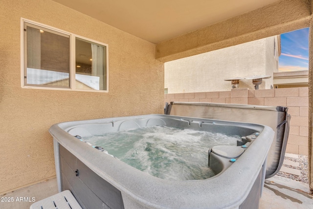 exterior details featuring a jacuzzi and stucco siding