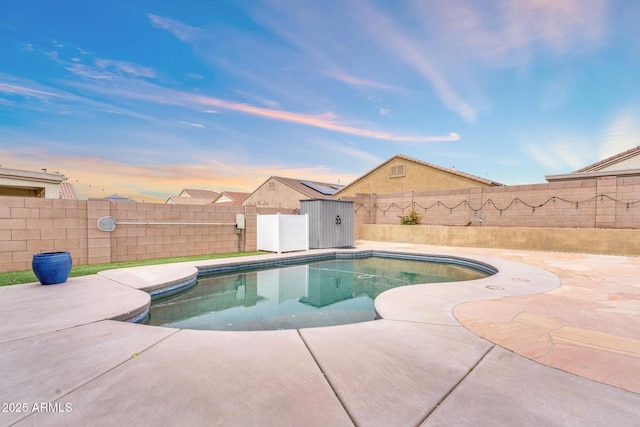 view of swimming pool featuring a fenced in pool, a fenced backyard, an outdoor structure, a storage shed, and a patio area