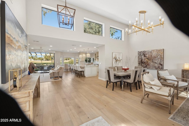 dining space featuring light wood-type flooring, a chandelier, and a high ceiling