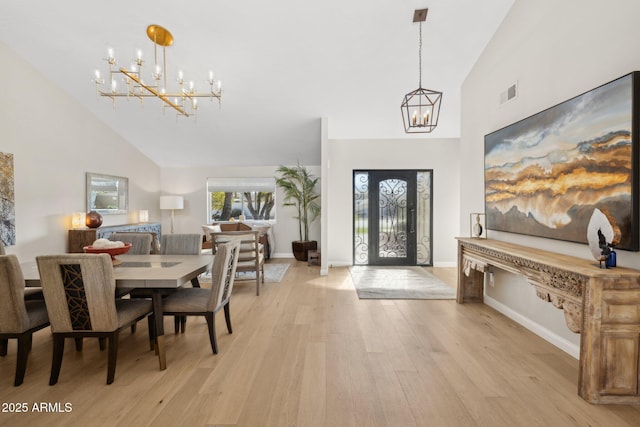 foyer entrance featuring high vaulted ceiling, light wood-type flooring, and an inviting chandelier