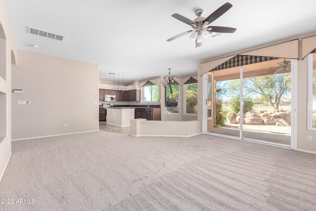 unfurnished living room featuring sink, ceiling fan with notable chandelier, and light colored carpet