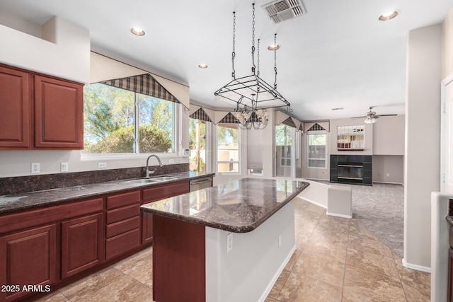 kitchen with a breakfast bar, pendant lighting, sink, a tiled fireplace, and a center island