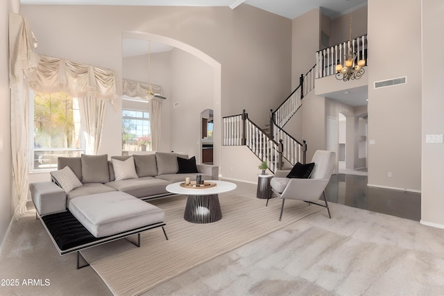 carpeted living room with a high ceiling and an inviting chandelier