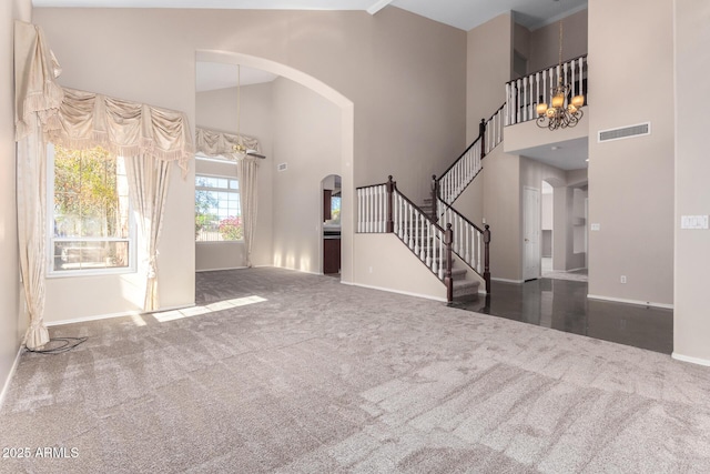 interior space with high vaulted ceiling, a chandelier, and dark carpet