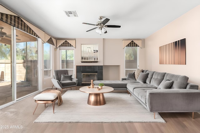 living room featuring hardwood / wood-style flooring, ceiling fan, and a fireplace