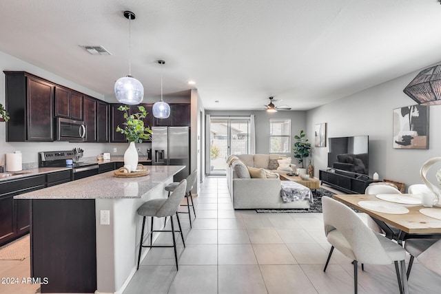 kitchen featuring appliances with stainless steel finishes, decorative light fixtures, a kitchen bar, a center island, and dark brown cabinets