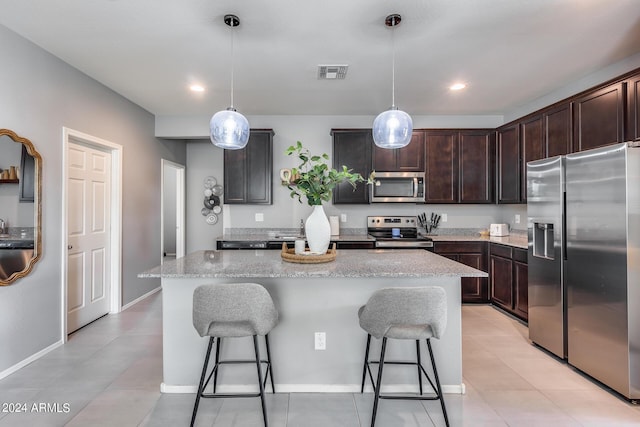 kitchen featuring hanging light fixtures, a kitchen island, appliances with stainless steel finishes, and dark brown cabinetry