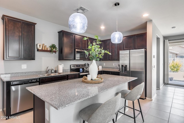 kitchen featuring dark brown cabinetry, appliances with stainless steel finishes, and hanging light fixtures