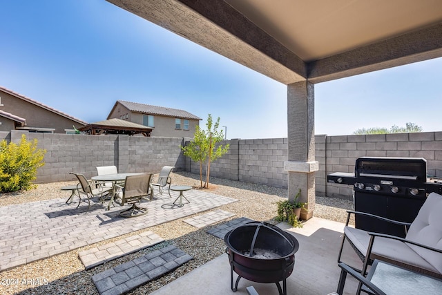 view of patio with area for grilling and a fire pit