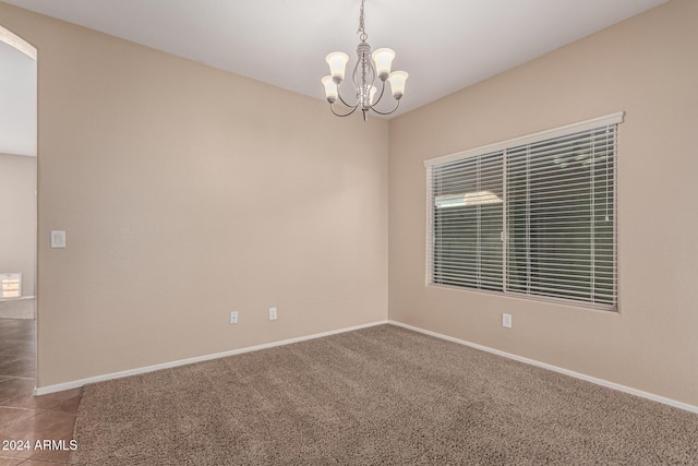 empty room with carpet floors and a chandelier