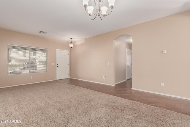 carpeted empty room with an inviting chandelier