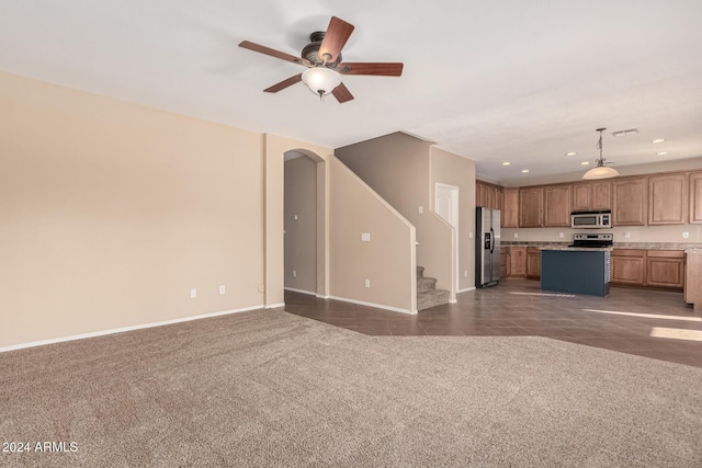 unfurnished living room featuring ceiling fan and dark carpet