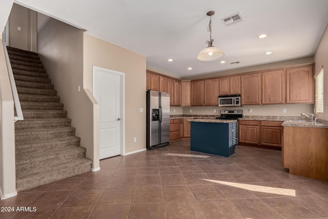 kitchen with a center island, sink, hanging light fixtures, stainless steel appliances, and dark tile patterned flooring