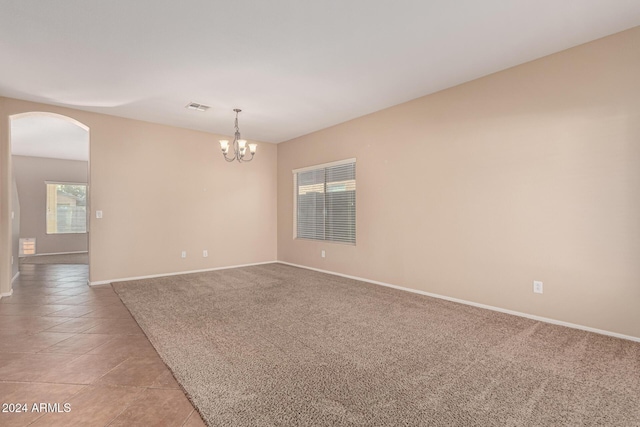 unfurnished room with light carpet and an inviting chandelier