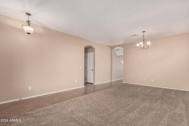 carpeted empty room featuring a notable chandelier