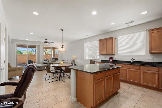 kitchen with light tile patterned flooring, ceiling fan, pendant lighting, sink, and a center island