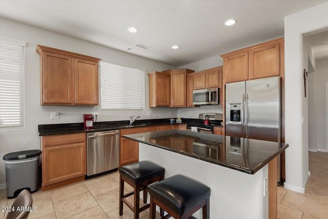 kitchen featuring light tile patterned floors, stainless steel appliances, sink, and a kitchen island