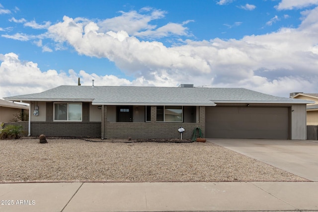 single story home featuring concrete driveway, brick siding, roof with shingles, and an attached garage