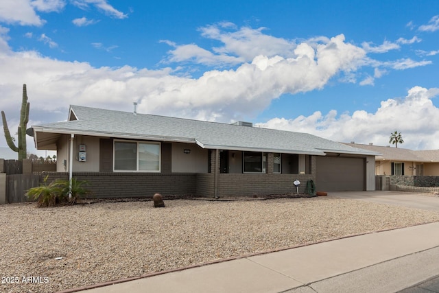 ranch-style house with driveway, a garage, roof with shingles, fence, and brick siding