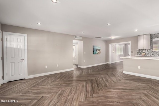 unfurnished living room with baseboards, visible vents, and recessed lighting