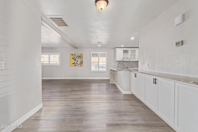 unfurnished living room featuring light hardwood / wood-style floors, a textured ceiling, and a wealth of natural light