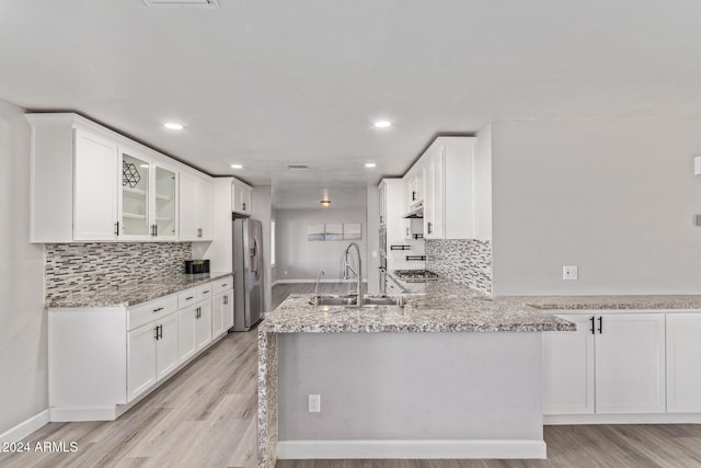 kitchen with appliances with stainless steel finishes, white cabinetry, light hardwood / wood-style flooring, and sink