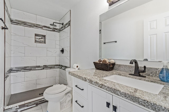 bathroom with tiled shower, vanity, and toilet