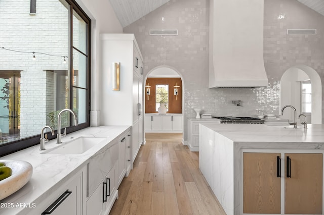 kitchen featuring white cabinetry, sink, and light stone counters