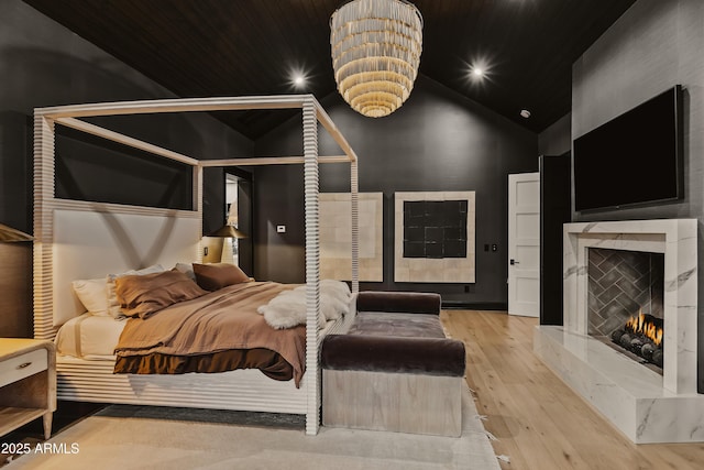 bedroom with high vaulted ceiling, light hardwood / wood-style floors, and a premium fireplace