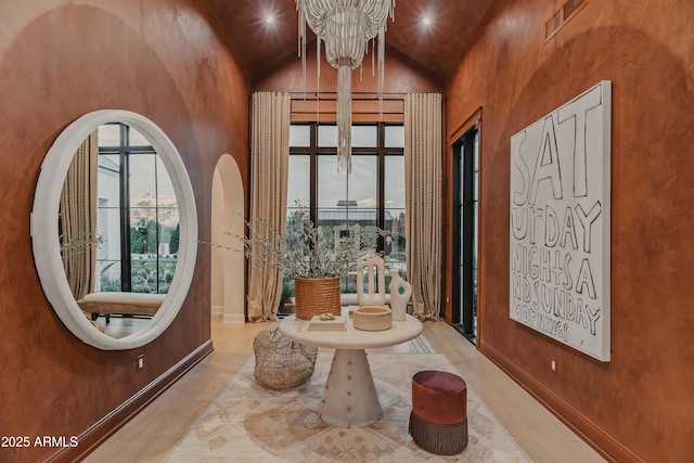 foyer featuring an inviting chandelier, high vaulted ceiling, and light hardwood / wood-style floors