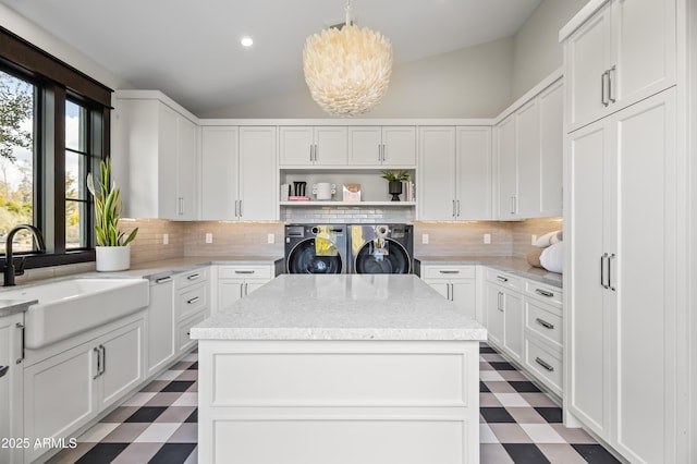 kitchen with sink, washing machine and dryer, a center island, and white cabinets