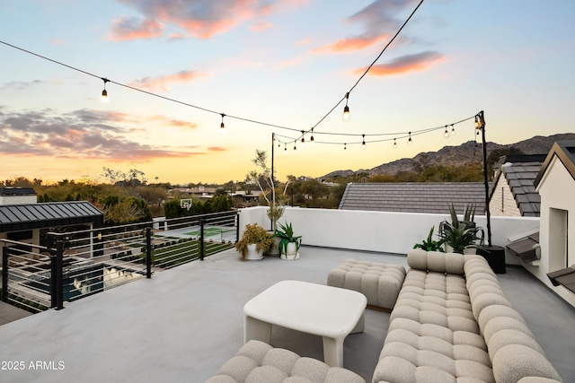 patio terrace at dusk featuring a balcony and a mountain view