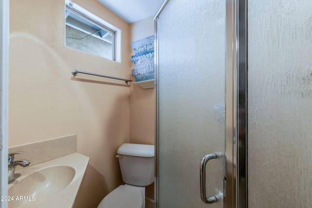 bathroom with sink, a shower with door, and toilet