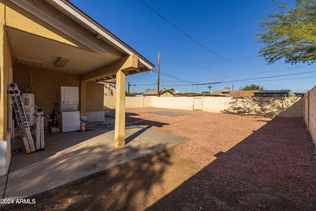 view of yard featuring a patio area, stacked washing maching and dryer, and water heater