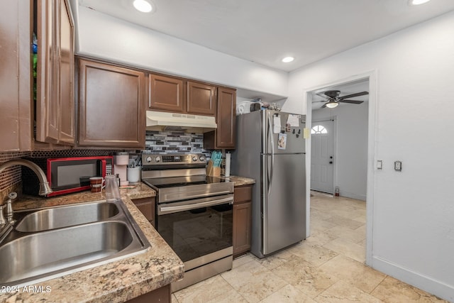 kitchen with ceiling fan, sink, light stone counters, decorative backsplash, and appliances with stainless steel finishes