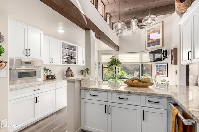 kitchen with white cabinetry, stainless steel oven, beam ceiling, and light stone countertops