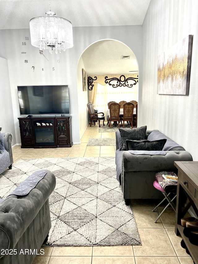 tiled living room featuring a textured ceiling and a chandelier